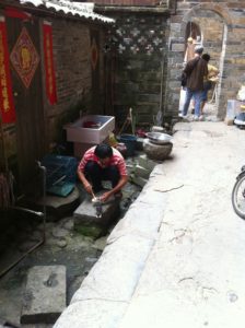 土楼の中で鳩に餌をやる中国人